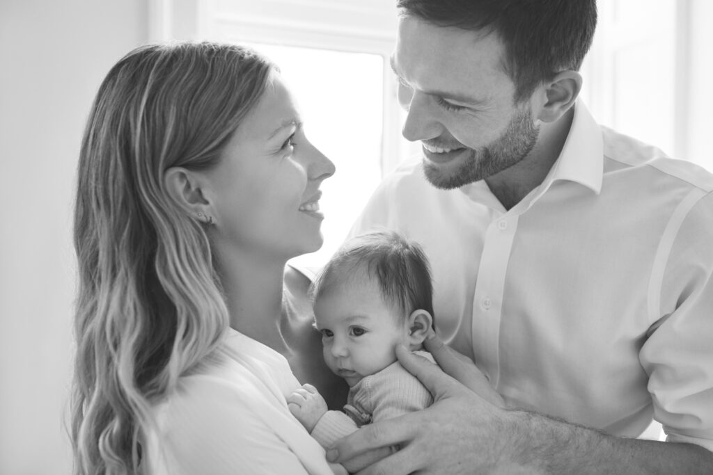 Smiling parents looking at each other holding their newborn baby in their arms