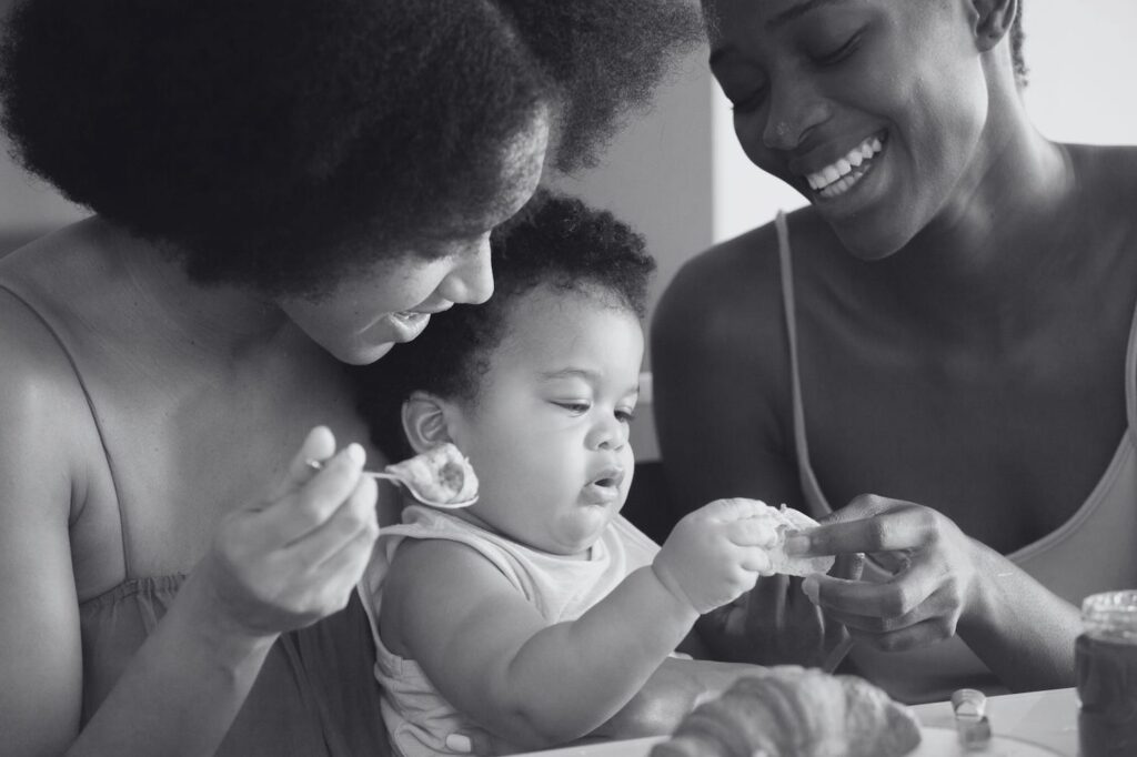 Two happy mothers feeding their baby, representing the successful outcome of embryo cryopreservation