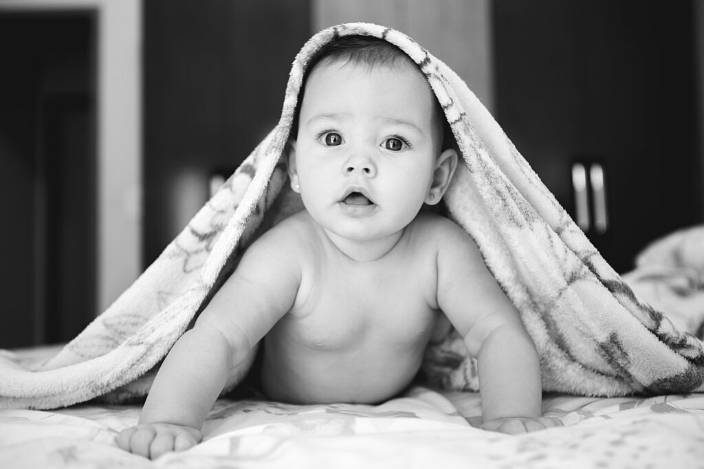 Happy baby under blanket, representing successful IVF outcome despite embryo grading concerns