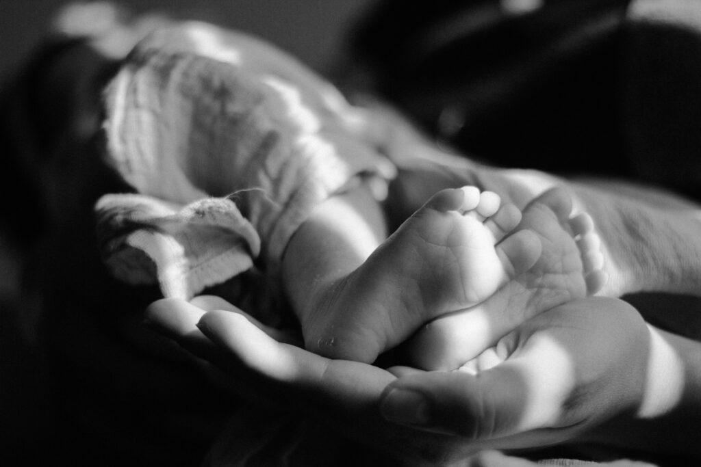 Newborn baby feet held in parent's hands