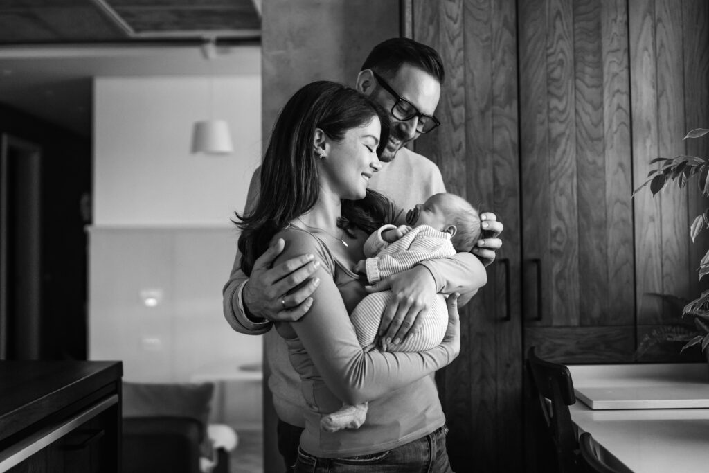 Happy parents holding their newborn baby at home, celebrating the outcome of a successful IVF journey