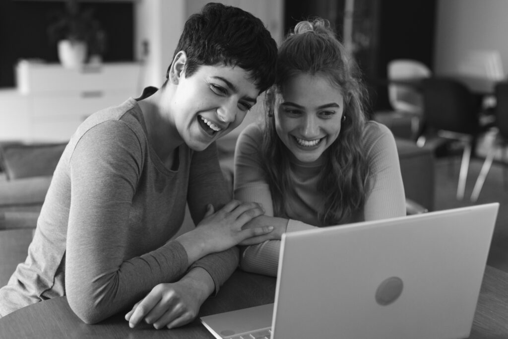 Happy lesbian couple looking at a laptop, taking the first step in the frozen embryo transportation process