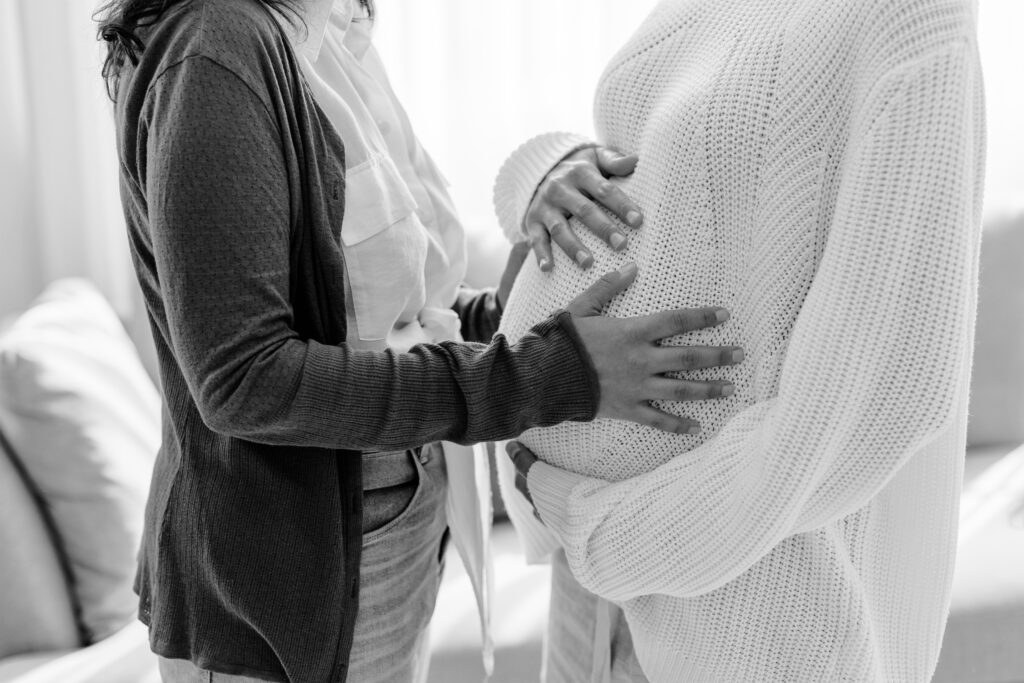 Intended parent gently touching surrogate's pregnant belly during surrogacy journey