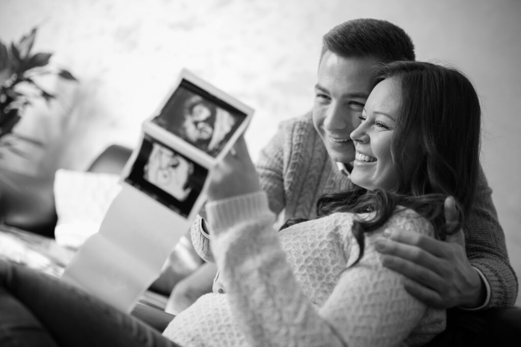 Happy intended parents looking at ultrasound photos, representing successful fertility planning