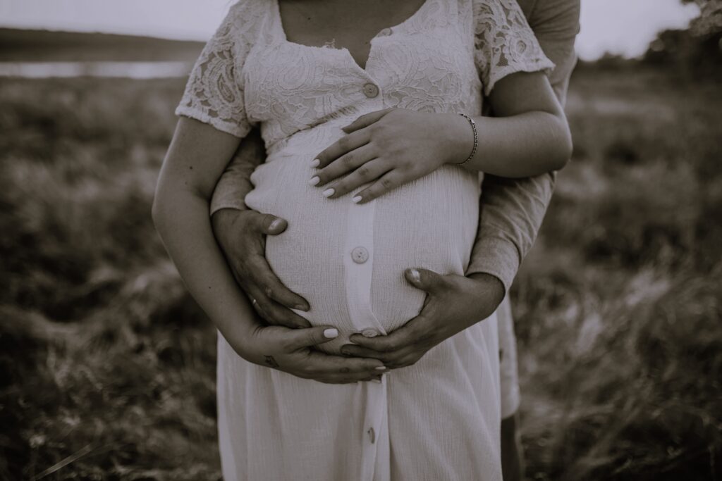hands of future mother and father clasped pregnant big tummy. Happy intended parents