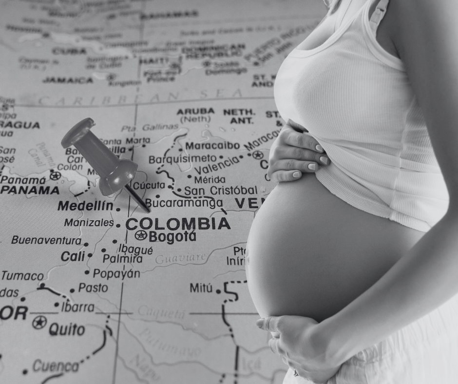 A women holding her pregnant belly with a map of Colombia as a backdrop