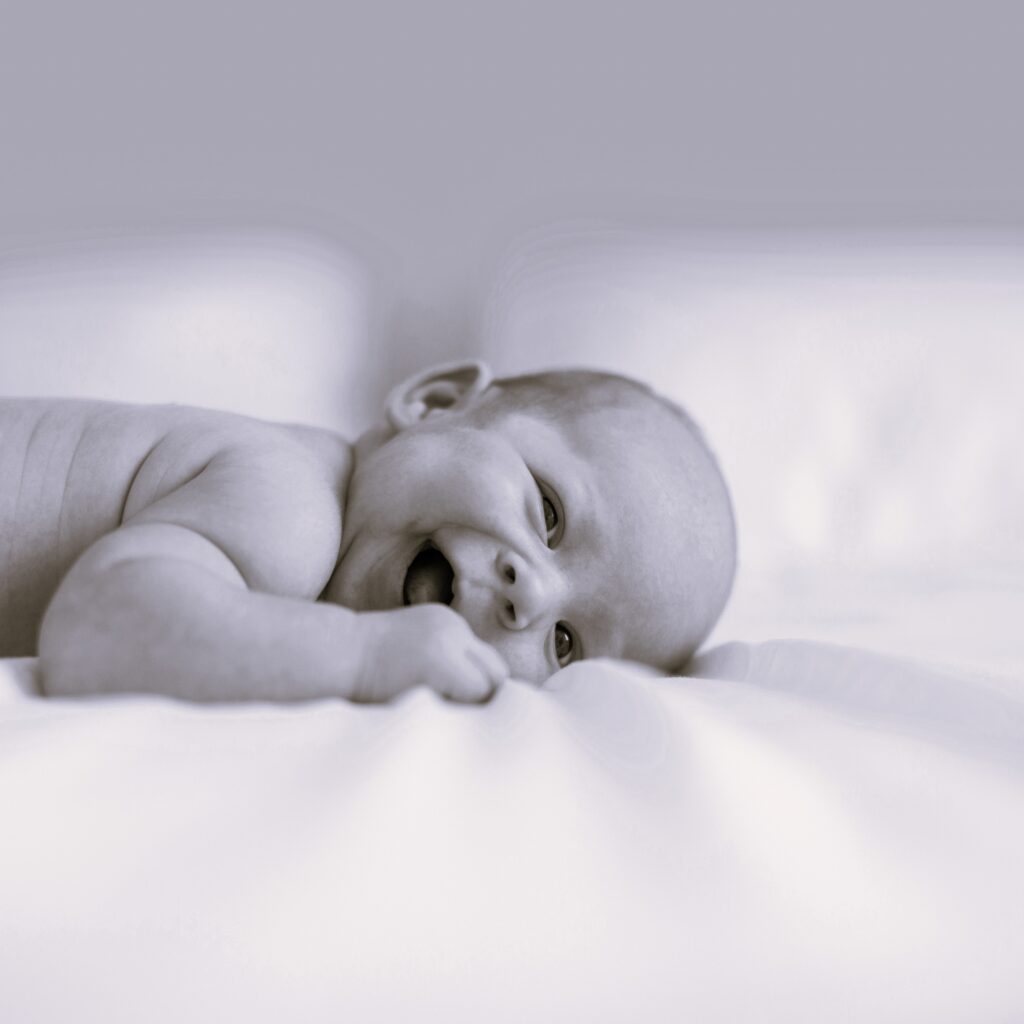 A close up of a baby laying down smiling